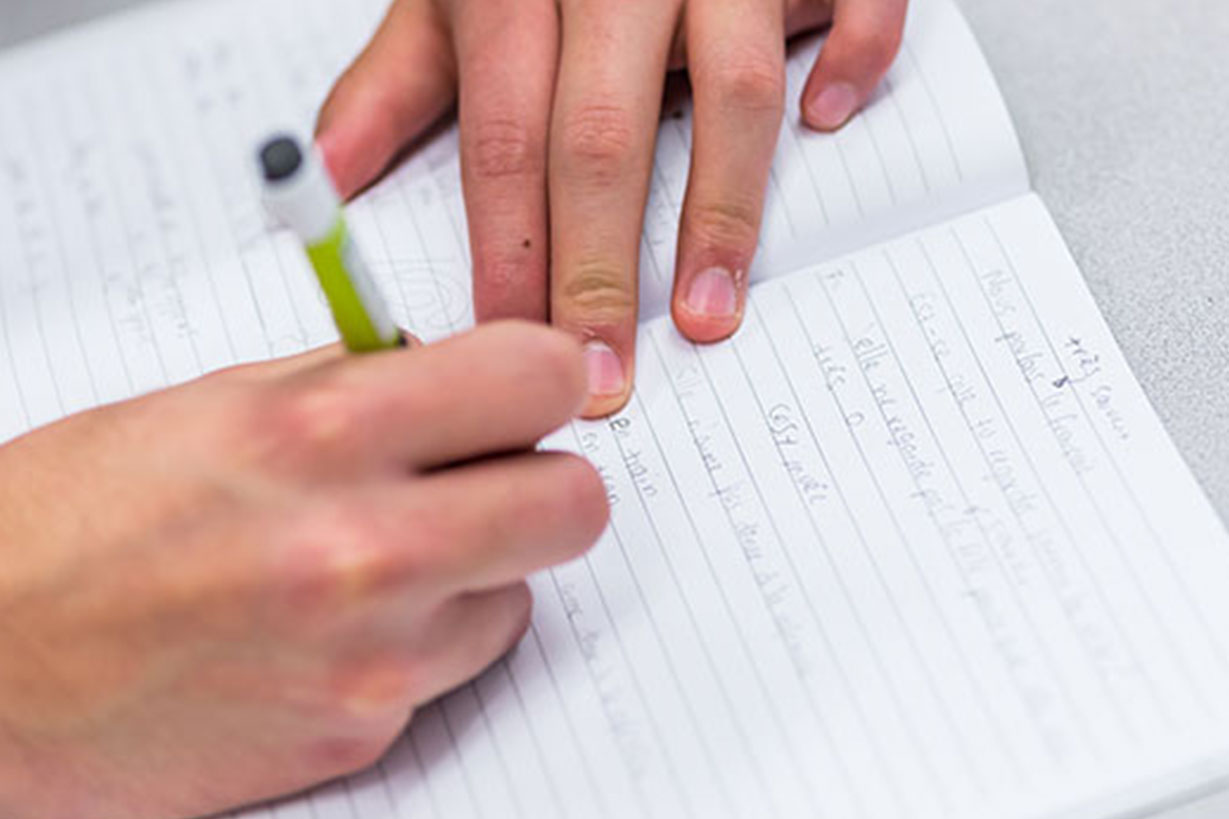 hands writing on a piece of white paper