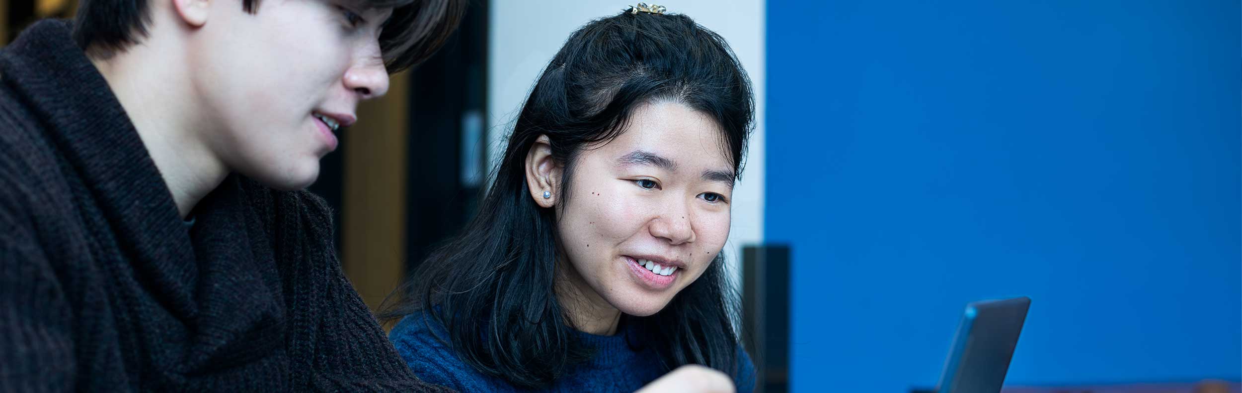  a male and a female smiling looking at a laptop 
